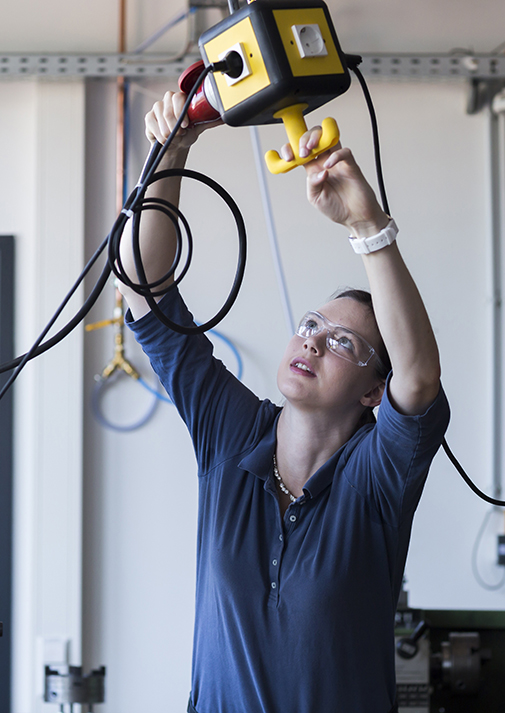 Young woman with safety goggles installing a three-phase plug